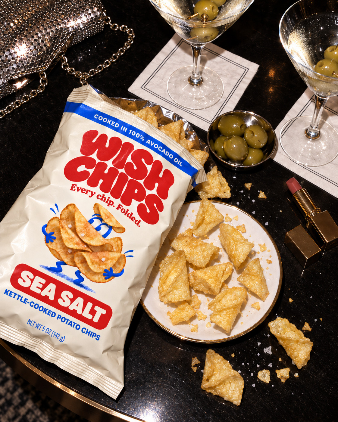 An open Wish Chips bag and a plate of chips beside martinis on a dark hotel bar table.