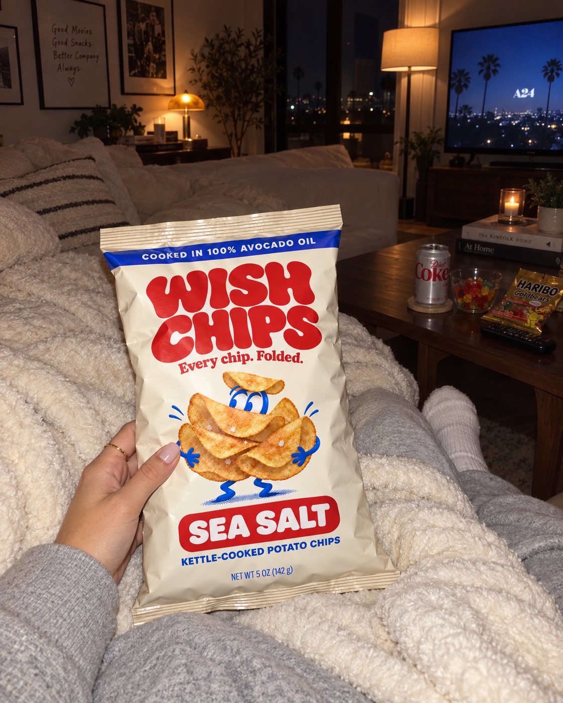 A Wish Chips bag held over a soft blanket during a cozy movie night at home.