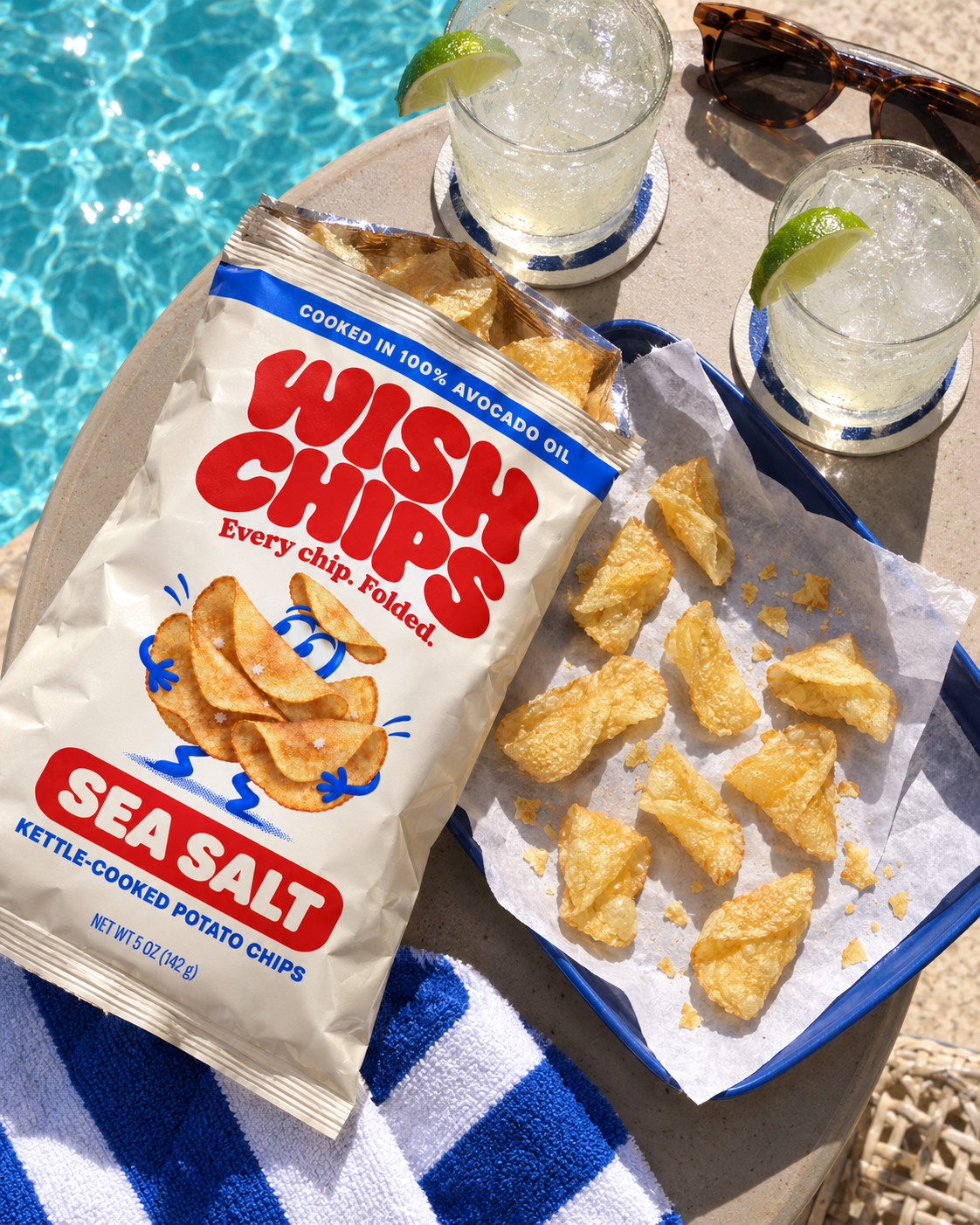 A Wish Chips bag beside a generous spread of golden chips, lime drinks and sunglasses by a blue pool.